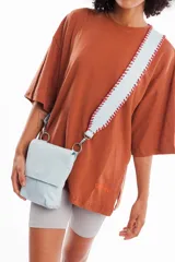 Bandolera celeste de cuero vacuno con correa trenzada hecha a mano, forro interior y broche imán en la tapa.