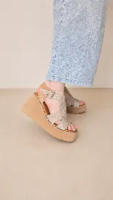 Sandalias de plataforma corrida color beige, con capellada de cuero y tira ajustable con hebilla en el tobillo.