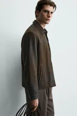 Cazadora regular fit de cuero marrón con efecto lavado vintage, cuello camisero, cierre frontal de cremallera y bolsillos de vivo en la cadera.