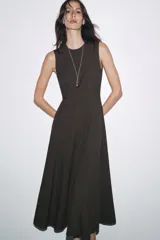 Vestido midi marrón sin mangas confeccionado en hilatura con 10% de lino. Tiene cuello redondo, corte evasé y cierre trasero con cremallera oculta.
