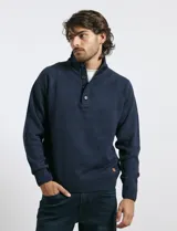 Sweater de punto color azul marino, con cuello alto, cierre frontal parcial y tapeta con botones. Presenta mangas raglán y puños y ruedo acanalados.