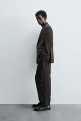 Pantalón de traje regular fit confeccionado en tejido de lana. Presenta bolsillos frontales, bolsillos traseros de vivo con botón y cierre frontal con cremallera y botón.