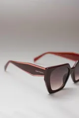 Lentes de sol hexagonales con marco color borgoña y lentes degradadas.