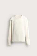 Camiseta relaxed fit de color blanco off-white, confeccionada en tejido texturizado con estructura. Presenta cuello redondo y manga larga.