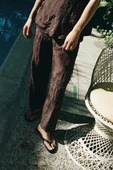 Pantalón de tiro medio y pernera recta, confeccionado en tejido de viscosa semitransparente. Presenta cintura elástica ajustable con cordón, bolsillos laterales y un diseño decorado con bordados a tono y aplicaciones de abalorios.