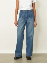 Jean de corte wide leg en color azul medio, con diseño de tiro alto y pinzas en la cintura. Presenta un estilo holgado y relajado con costuras reforzadas en el ruedo.