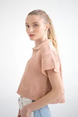 Sweater tejido de punto color rosa, con cuello polo, mangas cortas con detalle de calado y diseño geométrico en la parte inferior.