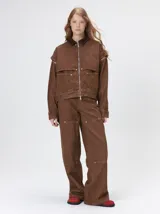 Campera de denim a rayas verticales con cuello de pana en color bordó. Presenta cierre frontal, mangas desmontables con cierre en los hombros, canesú en el pecho y bolsillos de parche cuadrados.