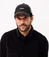 Gorra negra de algodón con visera curva, bordado frontal de la NASA en blanco y aplicación lateral de la bandera de Estados Unidos.