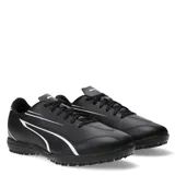Championes de fútbol 5 Puma modelo Vitoria TT, color negro con detalles en blanco. Presentan una suela de goma con relieve para mayor tracción en canchas de césped sintético y cierre mediante cordones.