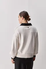 Sweater negro de tejido suave con escote redondo, mangas largas y calce relajado, con terminaciones acanaladas en cuello, puños y ruedo.