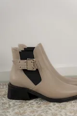 Botineta de cuero charol negro con acabado brillante, diseño de punta fina y taco cuadrado. Presenta un panel elástico lateral y una correa decorativa con hebilla metálica plateada.