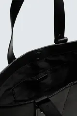 Bolso tipo shopper de diseño minimalista en color negro, con estructura vertical, doble asa de hombro y detalle de tira decorativa frontal con cierre magnético.