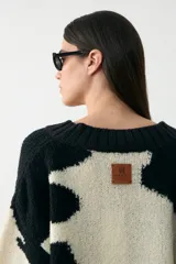 Sweater de tejido bouclé con diseño de animal print abstracto en blanco y negro, cuello en V y corte holgado.