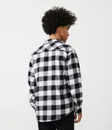 Camisa de manga larga confeccionada en franela de algodón, con estampado de cuadros en rojo y negro, cuello inglés y cierre frontal con botones.