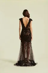 Vestido largo negro con escote en V, mangas cortas estilo cap y aplicaciones de encaje floral y bordados con pedrería sobre base de tul transparente.