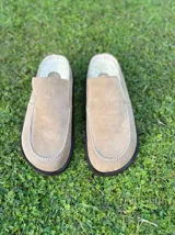 Zueco de cuero color marrón oscuro, con costuras decorativas en hilo rojo en el empeine y suela plana de goma.