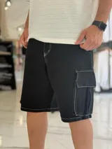 Bermuda cargo de denim negro con costuras en contraste de color blanco, corte holgado y bolsillos laterales con solapa.