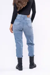 Jean corte mom de tiro alto, color azul claro con lavado clásico. Presenta cierre frontal con botón y cinco bolsillos tradicionales.