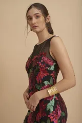 Vestido largo negro íntegramente bordado con lentejuelas en tonos fucsia y verde, con diseño floral, escote redondo y transparencias en la parte superior.