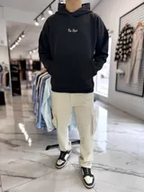 Canguro negro de corte oversize con capucha y gran estampa en la espalda de una rosa acompañada por la frase "Why fit in when you were born to stand out" y el texto "Top Style".