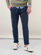 Pantalón chino azul marino de corte slim fit, confeccionado en gabardina con 77% algodón, 20% de algodón reciclado y 3% elastano. Presenta bolsillos delanteros y traseros. Tiene un lavado final con enzima ácida que le da un aspecto desgastado.