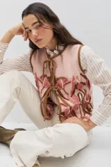 Chaleco de lana color rosa con bordados florales artesanales en tonos rosados y marrones. Presenta cierre frontal mediante lazos y terminaciones en color marrón.