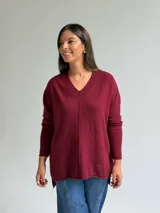 Sweater de punto color bordó, con escote en V, manga larga y costura central vertical decorativa.