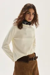 Sweater de punto color beige, con cuello redondo, manga larga y puños acanalados.