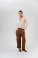 Pantalón barrel de gabardina de algodón color marrón, con cintura media-baja, cartera con botones semiocultos y recortes decorativos. Cuenta con bolsillos y detalles de botones en el ruedo para ajustar el volumen.