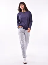 Remera negra de manga larga con cuello redondo y detalle de tachas doradas dispuestas en diagonal sobre el pecho.