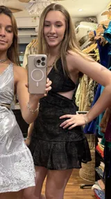 Vestido corto negro con estampado de plumas doradas, escote en V, breteles finos cruzados en la espalda, cut-outs laterales y volado en el ruedo.