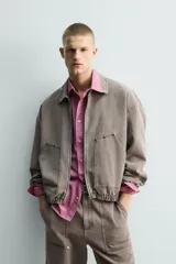 Cazadora de algodón de corte relajado, color marrón grisáceo con efecto lavado. Presenta cuello solapa con tachas metálicas, cierre frontal de cremallera, bolsillos de plastrón en la cadera y puños y bajo elásticos.