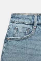 Falda pantalón de denim azul con diseño de cinco bolsillos, cierre frontal con cremallera y botón, y bajo deshilachado sin costuras.