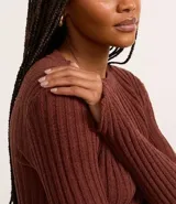 Blusa cropped color marrón, confeccionada en tejido de punto chenille texturizado, de corte ajustado, cuello redondo y mangas largas.