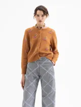 Cardigan de punto color marrón, con cuello redondo, cierre frontal de botones y mangas largas. Presenta un diseño bordado con motivos de cerezas realizados en canutillos.