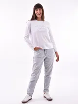 Remera de manga larga color crema con cuello redondo y un estampado central de un ramo de flores rosadas y naranjas en un jarrón azul oscuro.