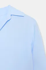 Camisa de manga larga color marrón oscuro, con cuello solapa, escote pico pronunciado y bajo asimétrico redondeado.