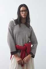 Sweater de punto a rayas horizontales en color marrón y blanco, con cuello polo y mangas largas con puños amplios. Presenta un diseño de calce relajado.
