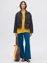 Campera de denim color negro con diseño de flecos en la parte frontal, cuello camisero y cierre frontal con botones metálicos.