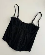 Corset negro de tirantes finos, con escote cuadrado y borde de encaje.