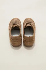 Zapatillas de estilo urbano color chocolate, confeccionadas en material textil tipo gamuza, con cordones al tono y suela de goma plana.