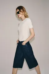 Bermuda de denim azul oscuro de tiro medio y corte recto, perteneciente a la ZARA Woman Collection. Cuenta con diseño de cinco bolsillos, trabillas para cinto y cierre frontal con cremallera y botón metálico.