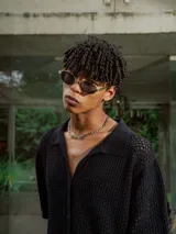 Camisa de manga corta color crudo/blanco, confeccionada en tejido de punto abierto con textura calada y cuello polo. Presenta cierre frontal de botones.