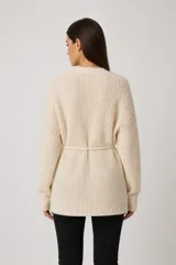 Cardigan de punto abierto, color natural, con diseño holgado, mangas largas y cuello en V. Presenta un cordón ajustable en la cintura.