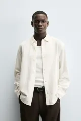 Camisa de corte regular fit confeccionada en tejido de algodón con textura de cuadrillé. Presenta cuello solapa, manga larga con puños abotonados y cierre frontal mediante botonadura.