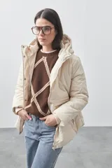 Campera puffer negra con diseño acolchado, capucha integrada y cierre frontal con botones a presión. Presenta puños elásticos y costuras decorativas en el frente.