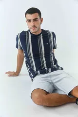Remera de hombre con diseño de rayas verticales en tonos azul marino y gris, cuello redondo y manga corta. Presenta un pequeño logo bordado en el pecho.