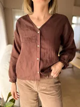 Camisa de lino color chocolate con cuello en V, cierre frontal de botones de nácar y mangas largas con puños.