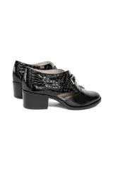 Zapato de tacón cuadrado color negro, confeccionado en cuero con combinación de texturas: efecto reptil en la parte trasera y cuero liso en la puntera. Presenta un diseño con aberturas laterales y cierre con hebilla dorada.